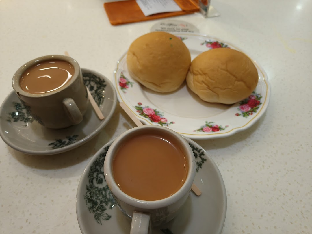 Two cups of traditional milk tea and two golden buns served on a table.