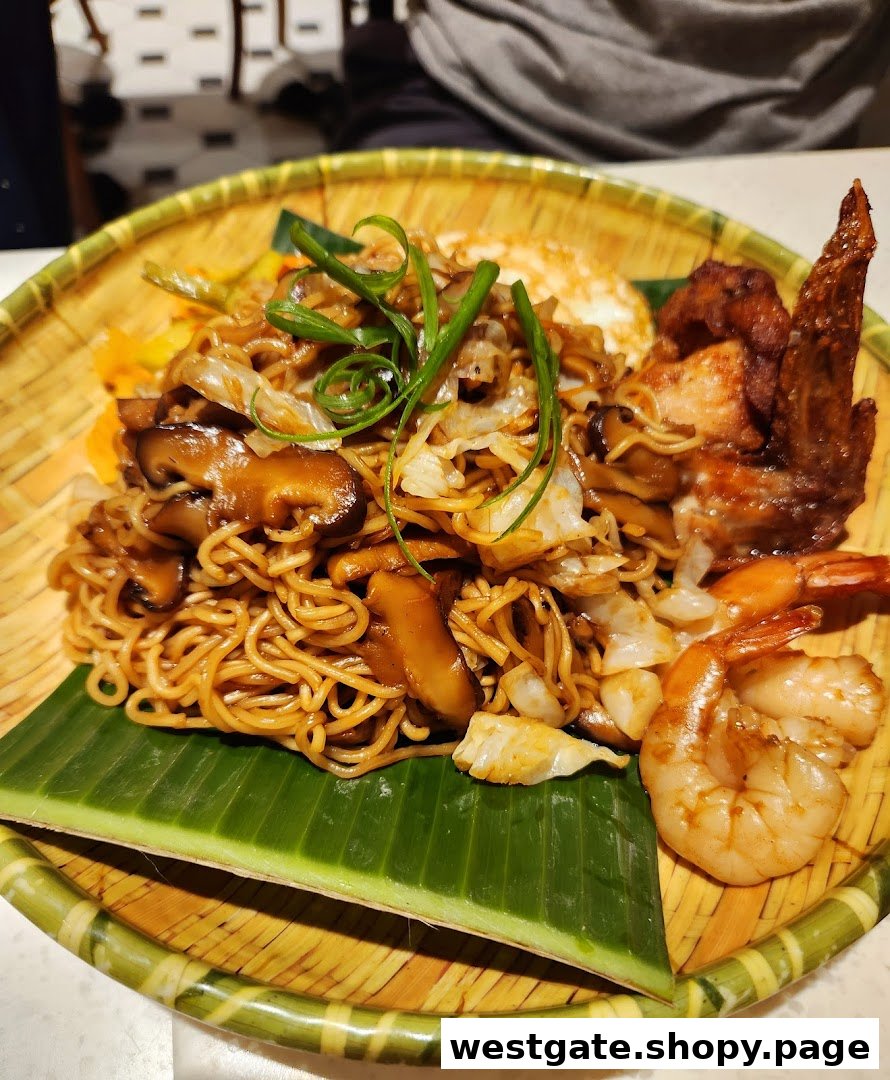 A delicious plate of noodles with mushrooms, chicken wing, and prawns served on a banana leaf.