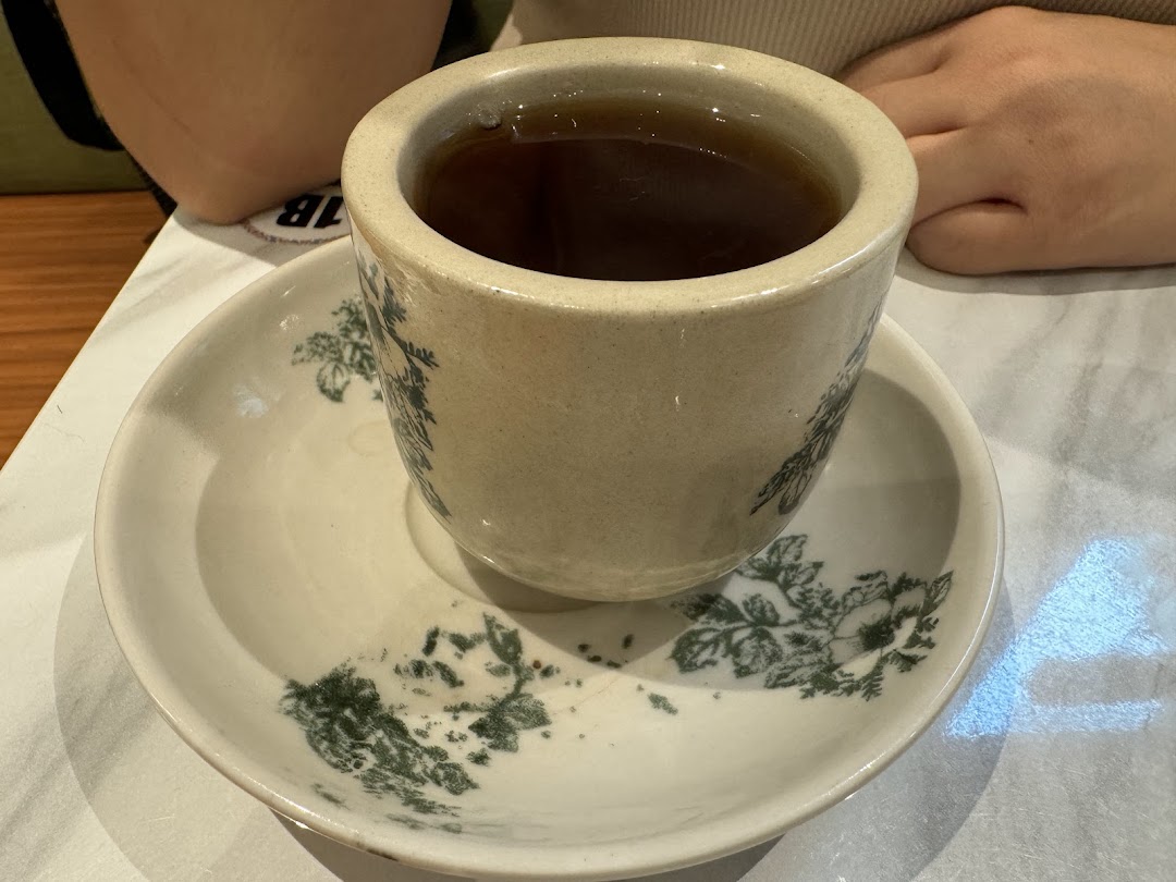 A traditional cup of hot beverage on a patterned saucer at Curry Times.