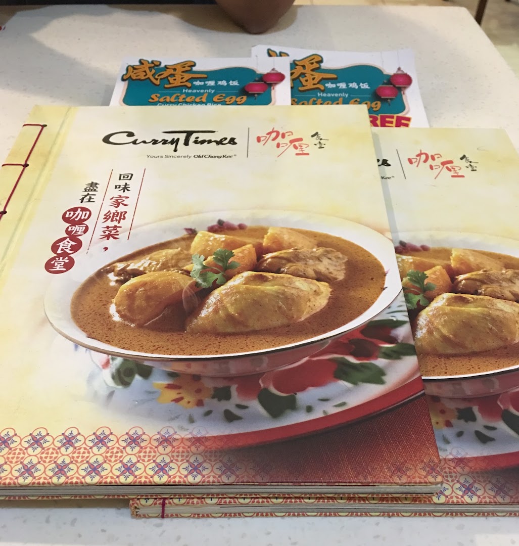 A Curry Times menu booklet cover featuring a delicious curry chicken dish and promotional flyers.