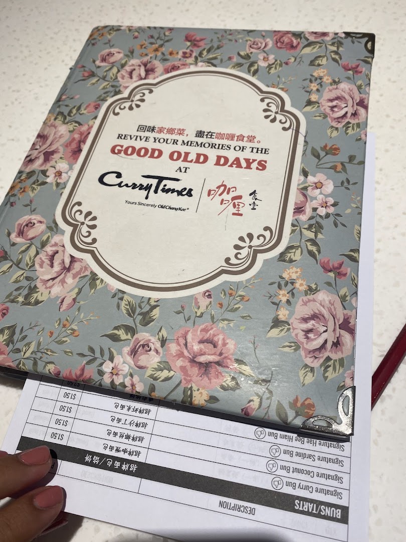 A vintage-style menu book from Curry Times with an order sheet showing bun and tart options.