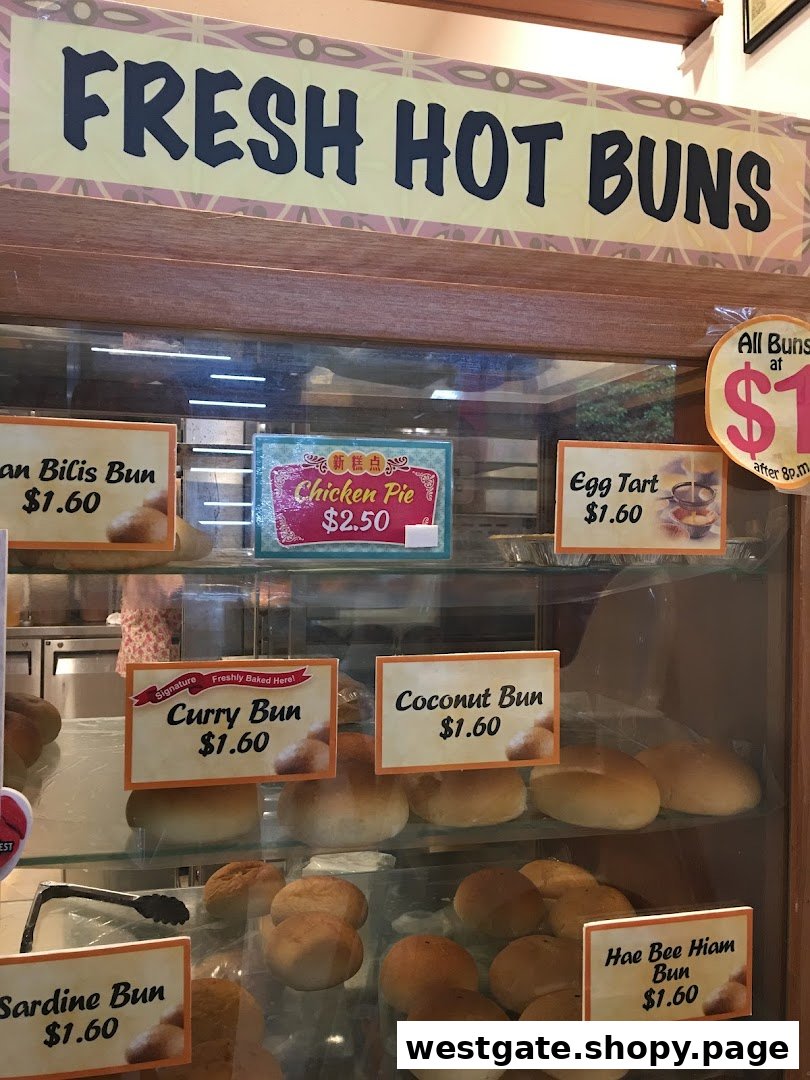 A display case showcasing a variety of freshly baked buns, pies, and tarts with prices.