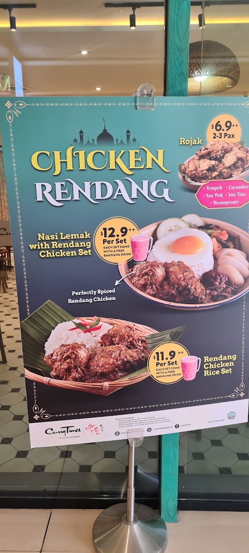 A promotional standee displaying Chicken Rendang dishes and prices from Curry Times.