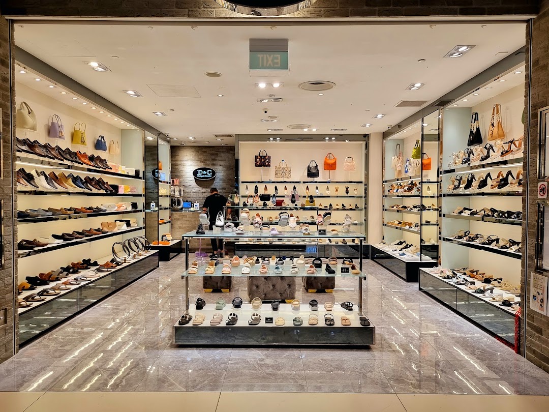 A well-lit shoe and accessory store entrance showcasing a wide variety of footwear and handbags.