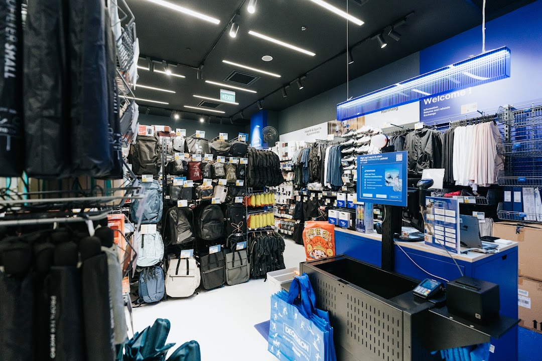 An interior view of Decathlon, showcasing a wide range of sports apparel, bags, and accessories, with a checkout counter visible.