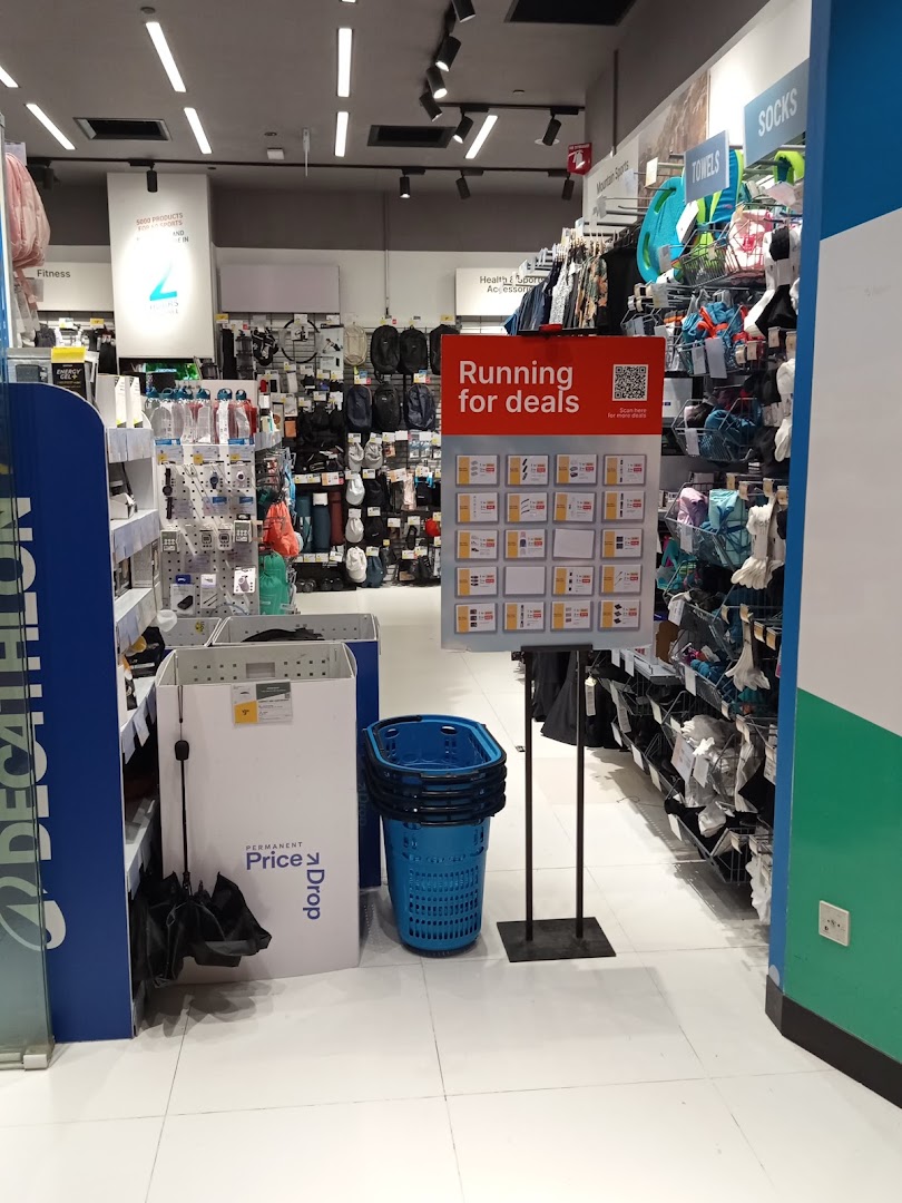 An interior view of Decathlon, showcasing sports apparel, accessories, and a 'Running for deals' display.