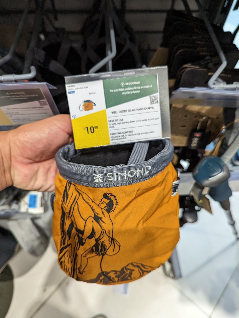 A hand holds a yellow climbing chalk bag with a $10.90 price tag and climber graphic.