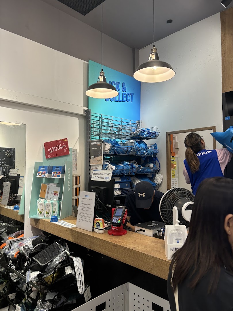 Decathlon's Click & Collect counter with staff assisting customers and sports equipment visible.