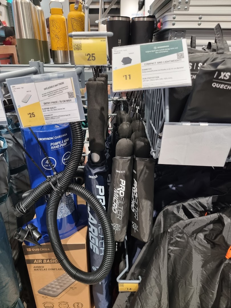 A retail display showcasing various outdoor and camping gear, including inflatable mattresses, hand pumps, and compact shelters.