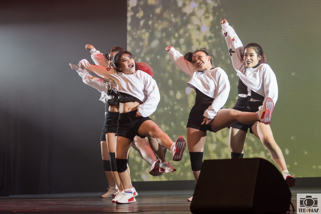 A group of young dancers performing on stage with dynamic poses and energetic expressions.