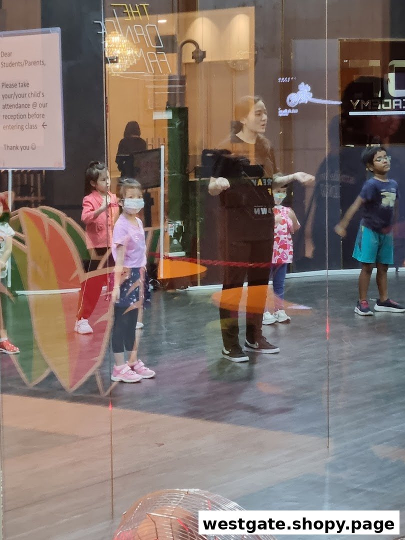 Children and an instructor engaged in a dance class, viewed through a glass window.