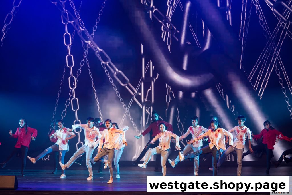 A group of young dancers performs on stage with dramatic lighting and a digital chain backdrop.