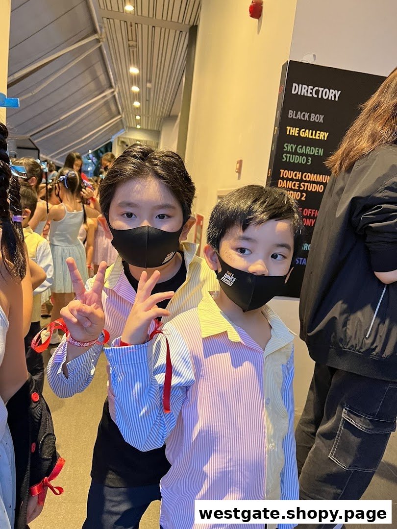 Two masked children pose in a hallway, with a directory sign and other students in the background.
