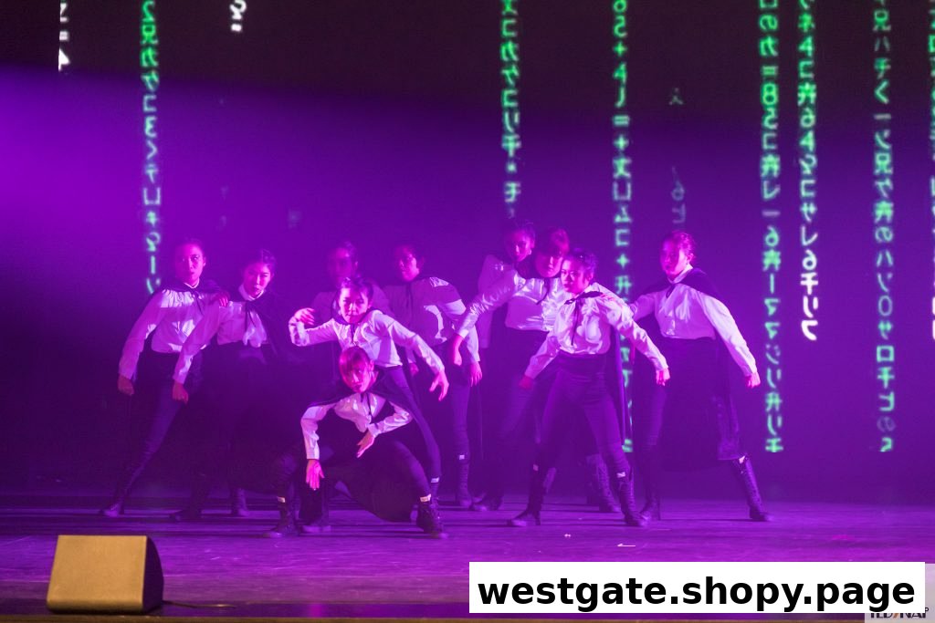 A group of performers in white shirts and black attire on a stage with purple lighting and digital projections.