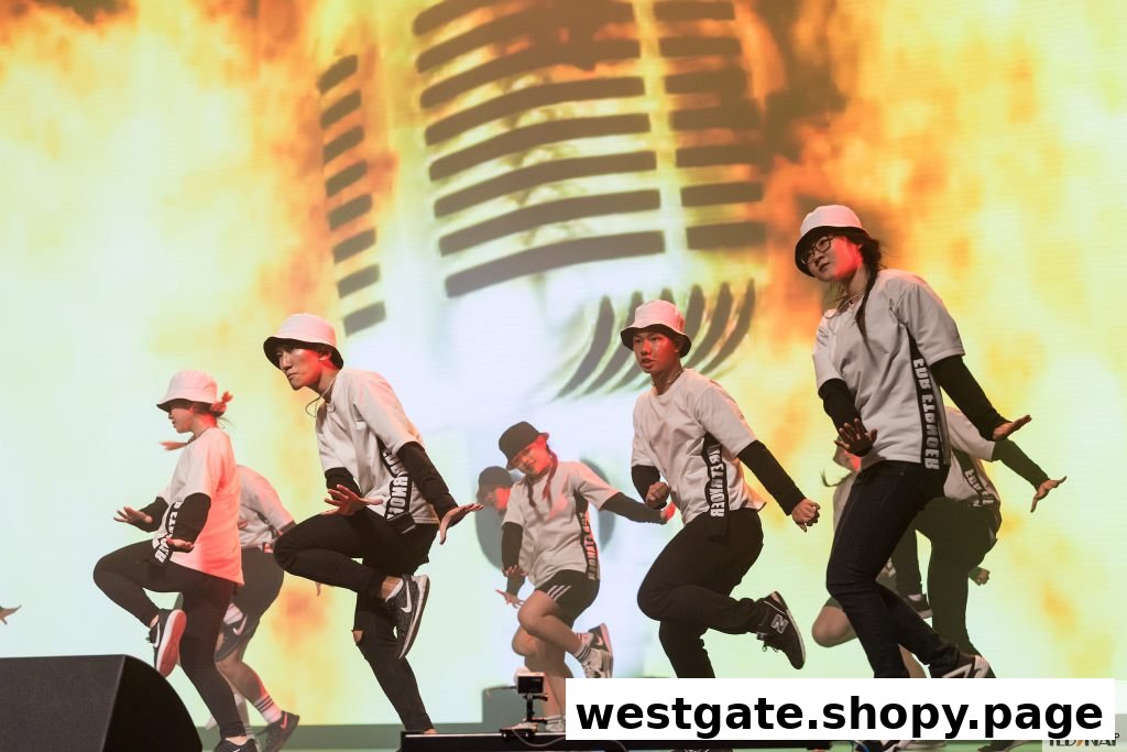 Energetic dancers in bucket hats perform on stage with a large microphone graphic backdrop.
