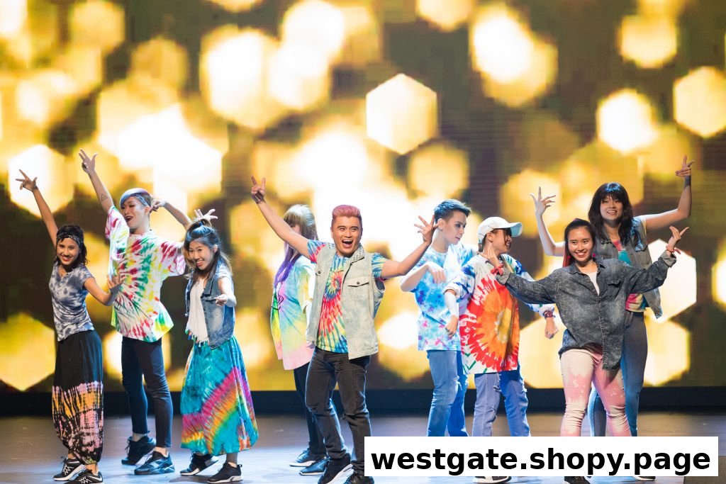 A diverse group of young people in vibrant tie-dye outfits posing energetically on a stage.