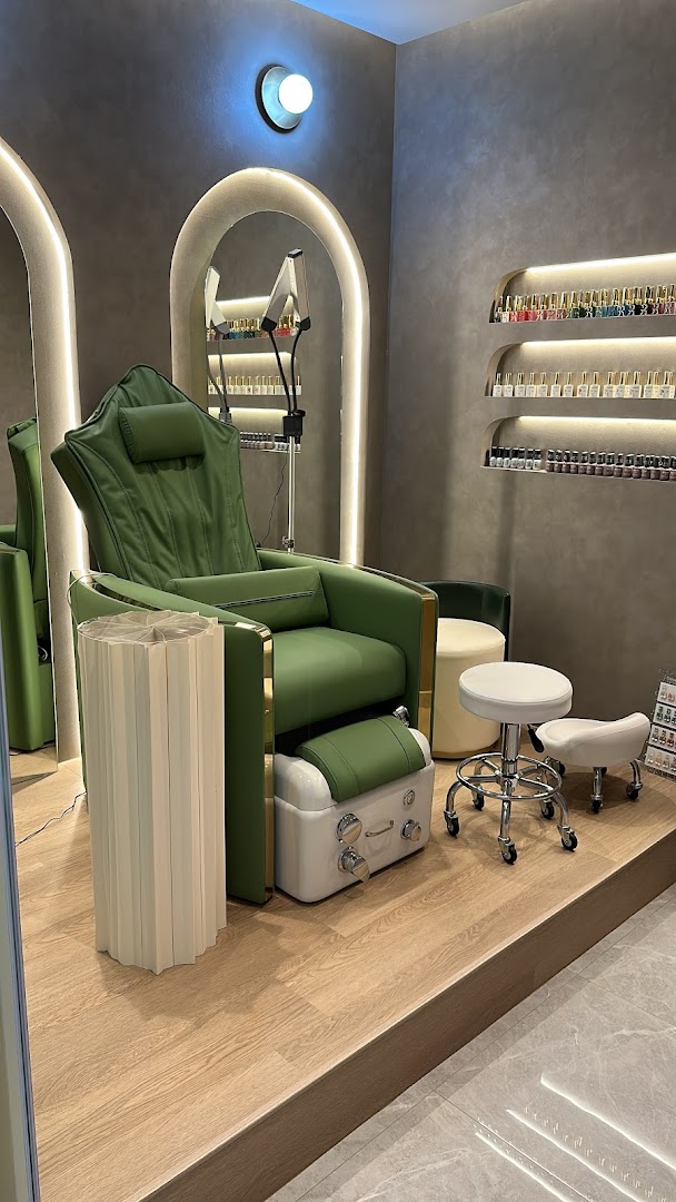 A modern salon interior featuring a luxurious green pedicure chair and shelves displaying nail polish.