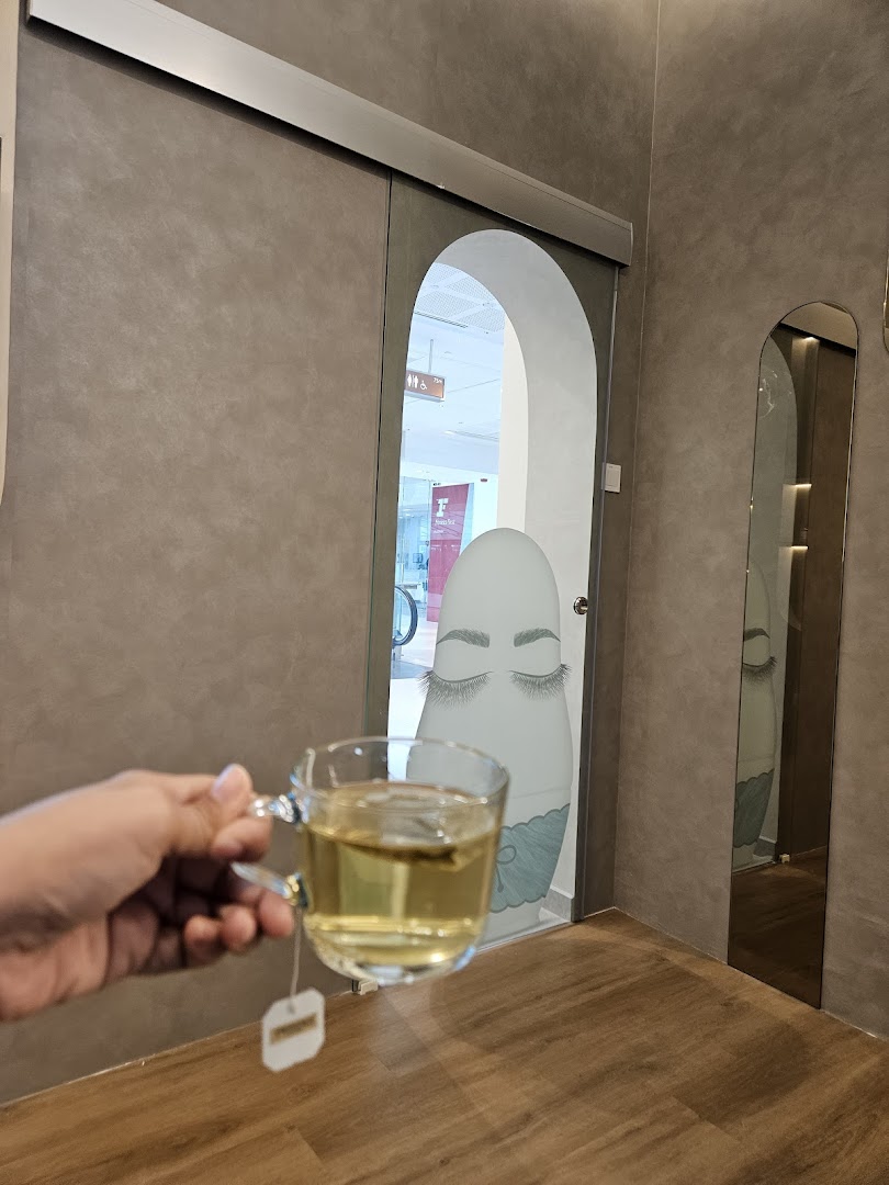 A hand holding a tea cup inside DR. LASH, featuring lash-themed decor and a relaxing ambiance.
