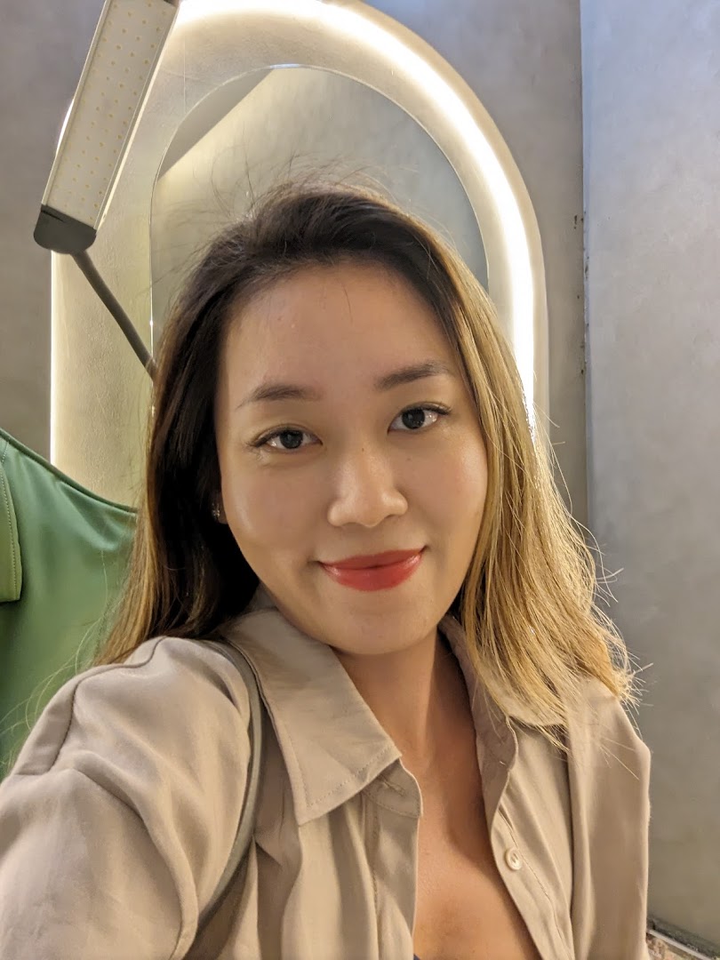 A smiling woman, likely a satisfied client, in a modern beauty salon setting.