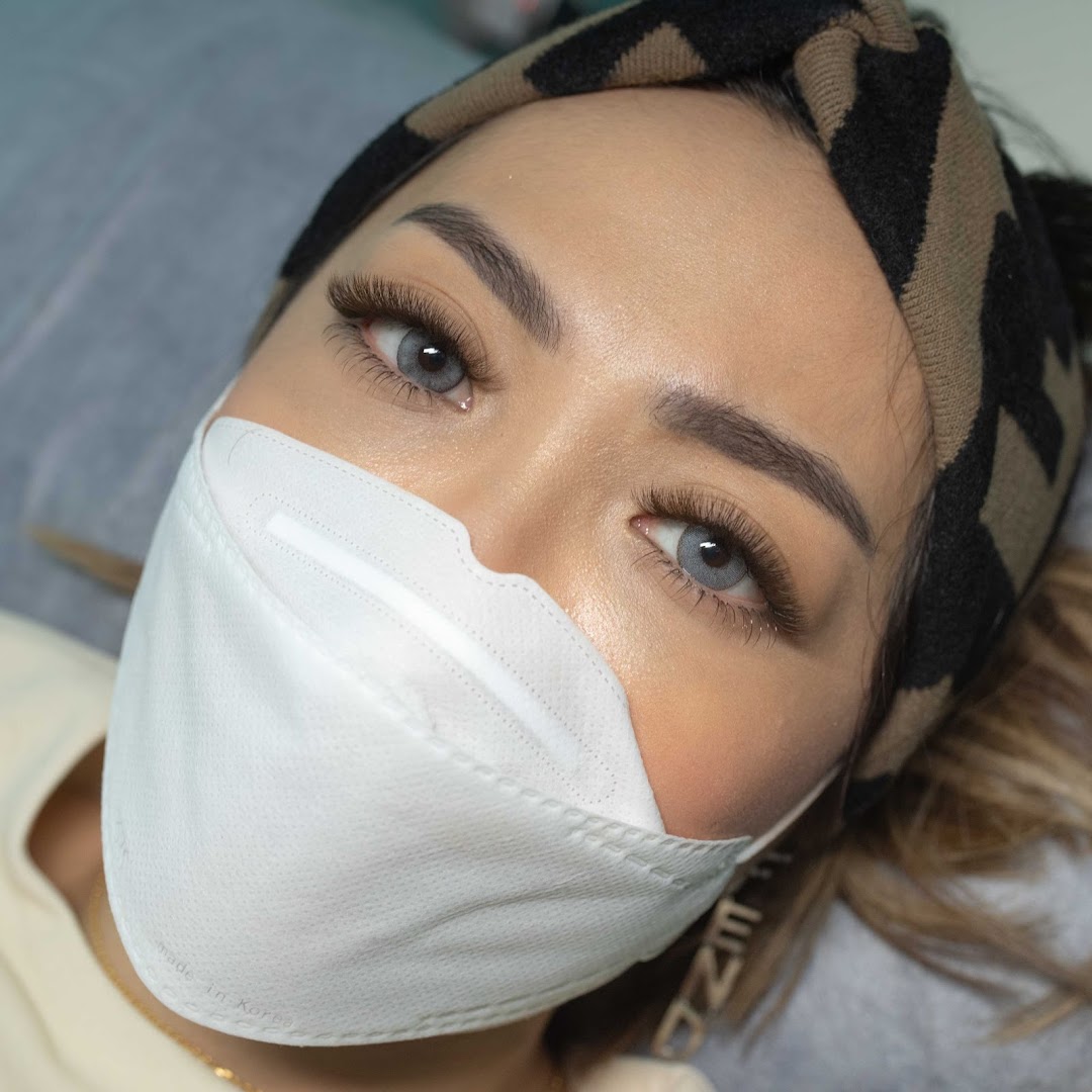 Close-up of a client showcasing beautifully applied lash extensions and perfectly shaped brows.