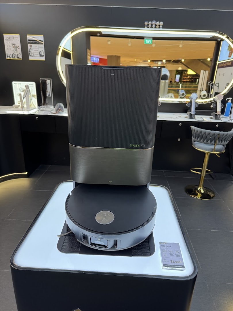 A Dreame robot vacuum/mop is displayed prominently in a modern retail store setting.