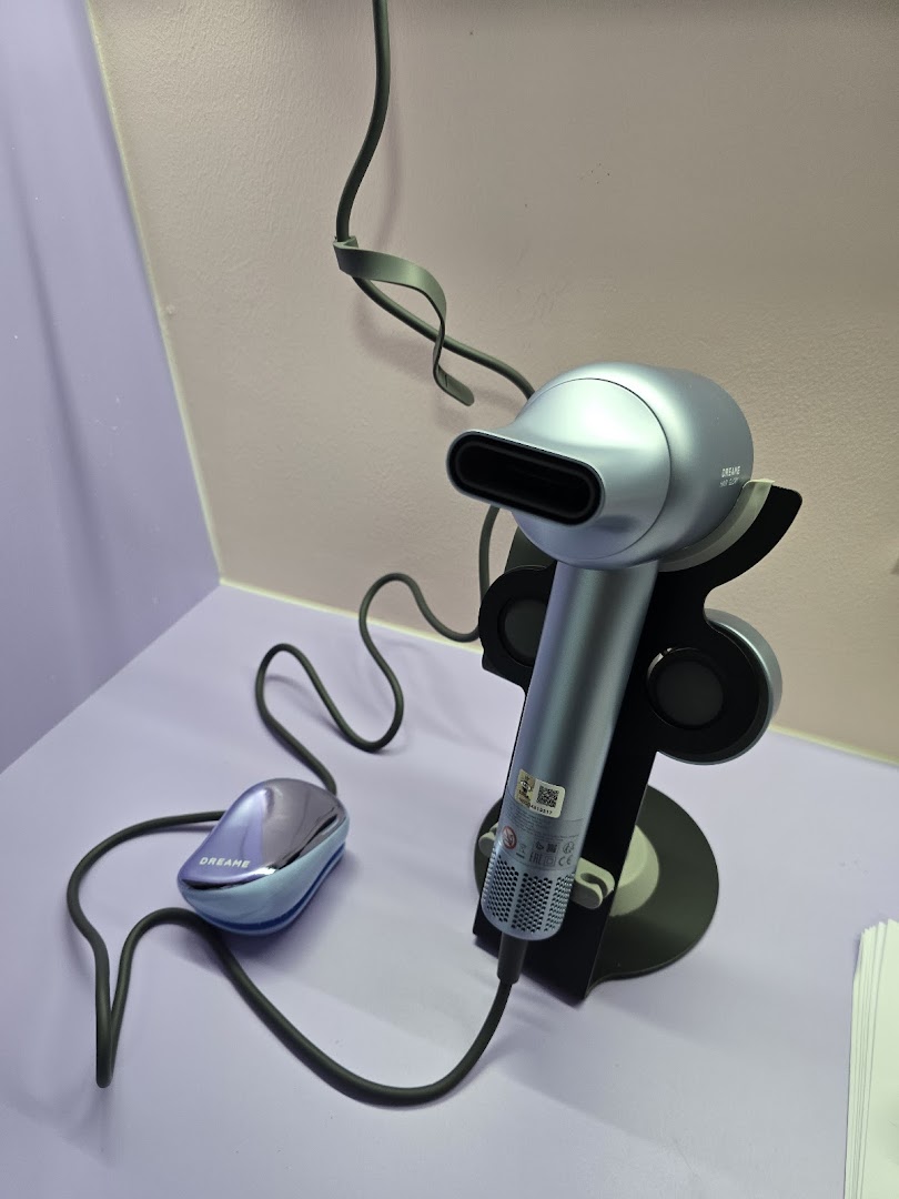 A sleek silver Dreame hair dryer and a smaller device displayed on a light purple surface.