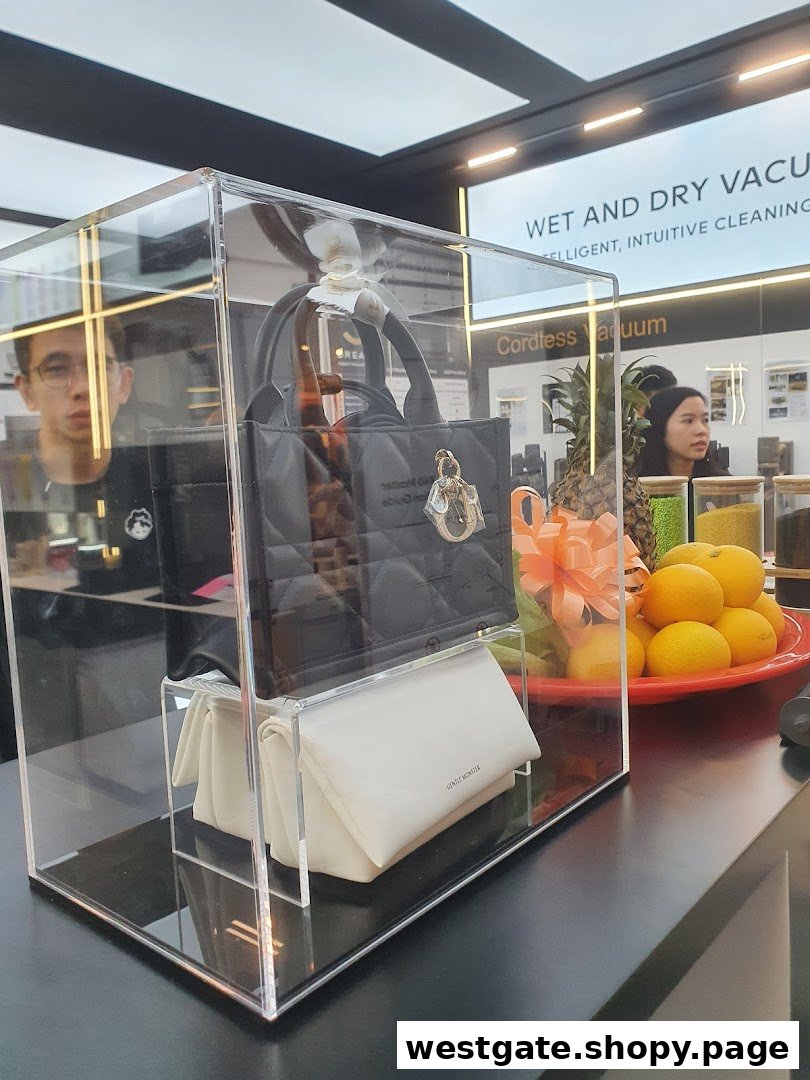 A modern retail display featuring a black handbag in a clear case, with home appliances visible in the background.