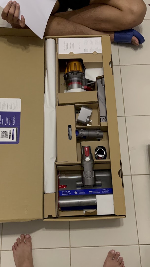 A new Dyson vacuum cleaner is unboxed, revealing its components neatly packed in the box.