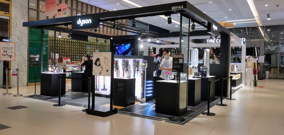 An interior view of the Dyson kiosk showcasing various home technology products and staff assisting customers.