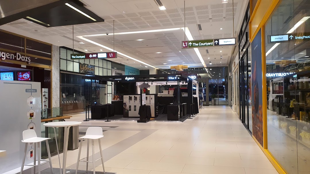 A Dyson kiosk showcasing innovative products in a brightly lit shopping mall hallway.
