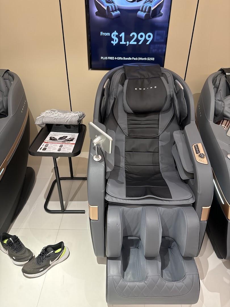 A grey EMPIRE massage chair displayed in a retail store, with a digital price sign.