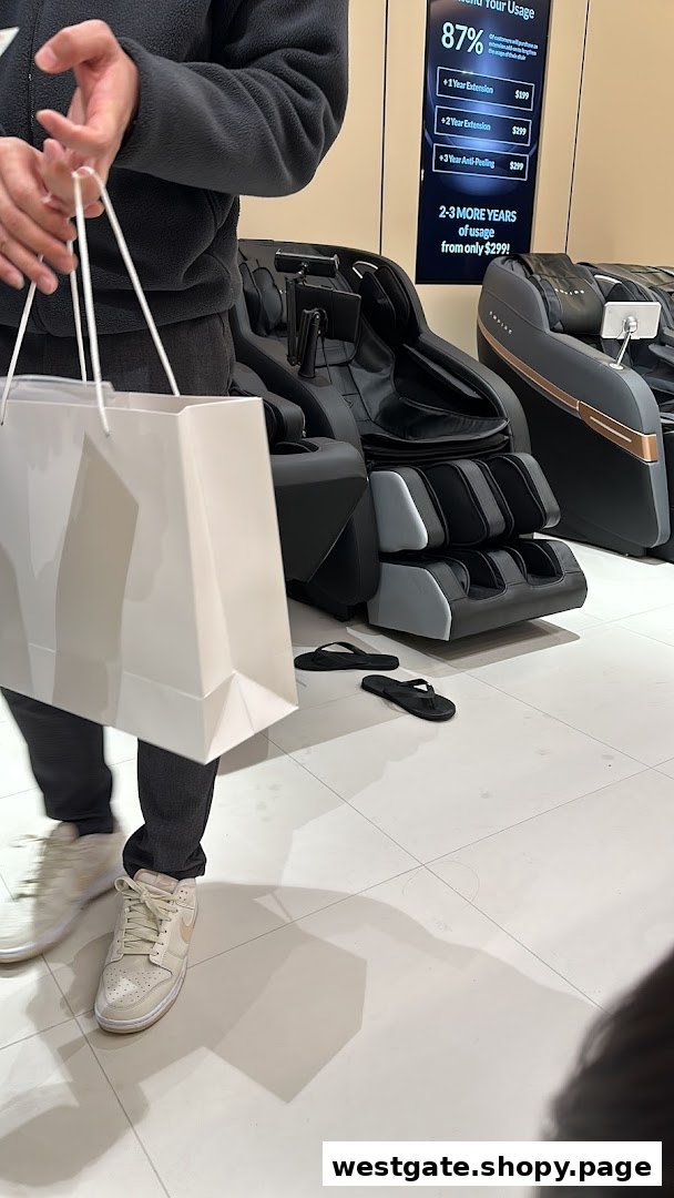 A person stands in a massage chair store, with various massage chairs and a digital display visible.