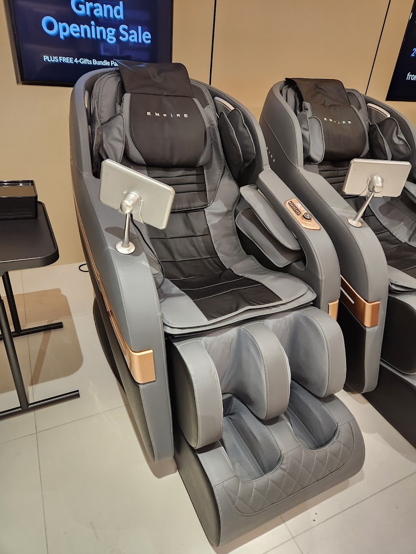 Two modern grey and black massage chairs with gold accents are displayed in a retail setting.