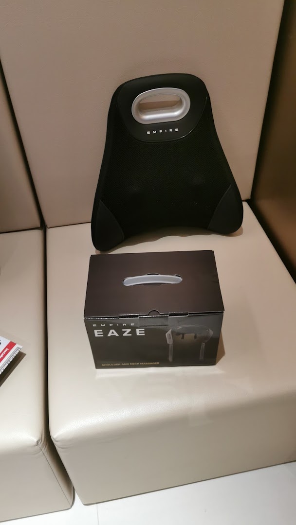 An Empire massage pillow and product box displayed on a light-colored sofa.