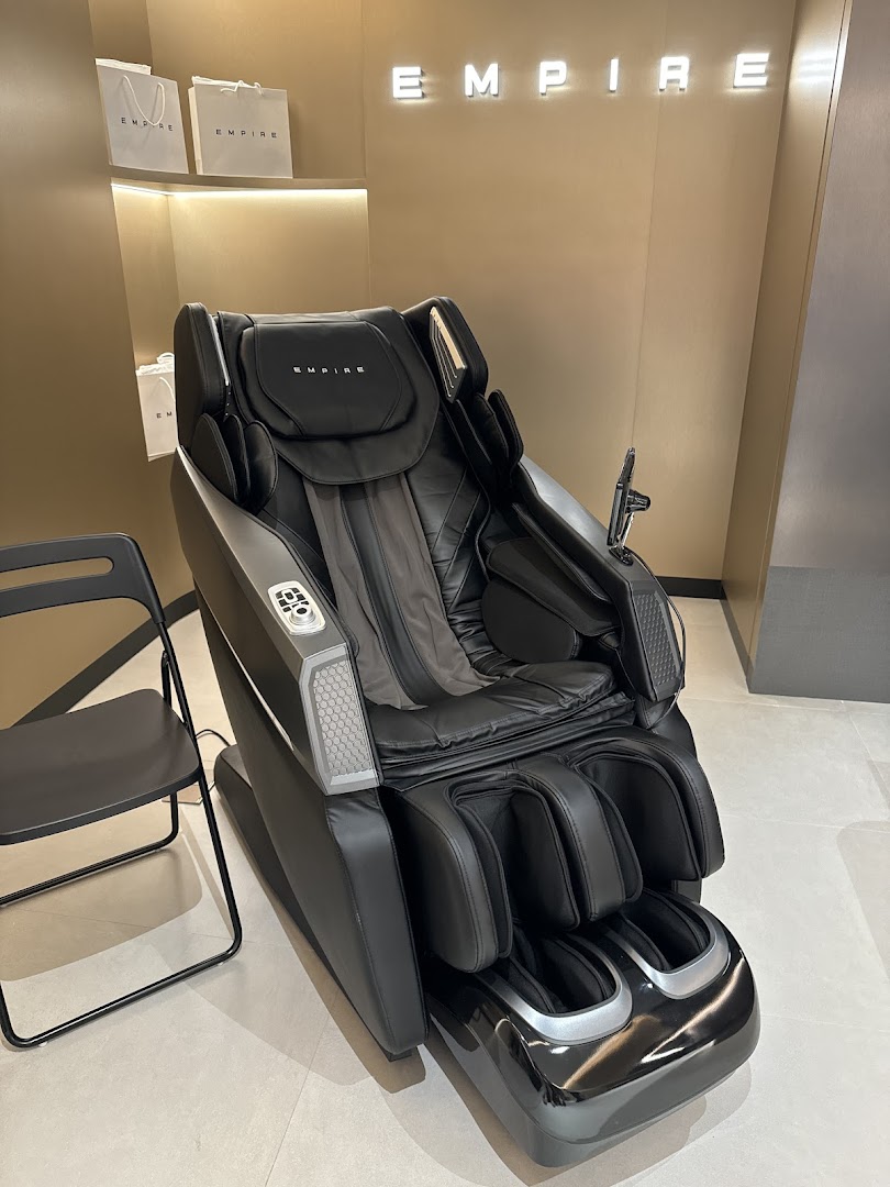 A luxurious black massage chair displayed in a modern retail setting under the 'EMPIRE' brand.