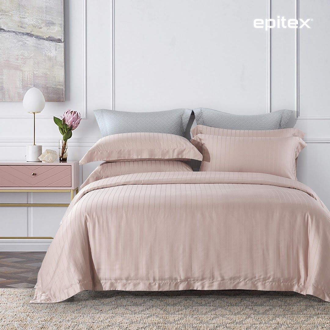 A beautifully styled bed featuring elegant pink striped bedding, pillows, and a chic bedside table.