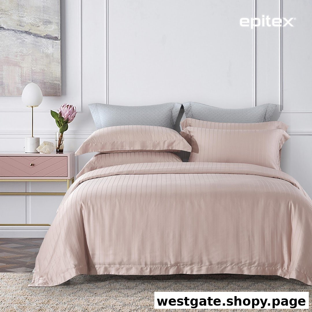 A beautifully styled bed featuring elegant pink striped bedding, pillows, and a chic bedside table.
