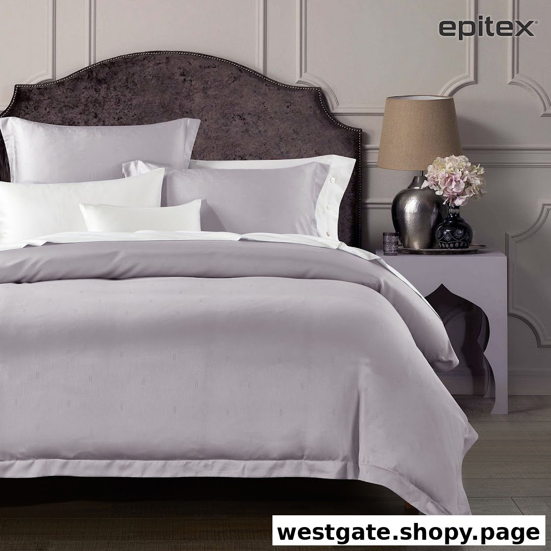 An elegantly styled bed featuring luxurious grey and white bedding from Epitex, complete with decorative pillows.