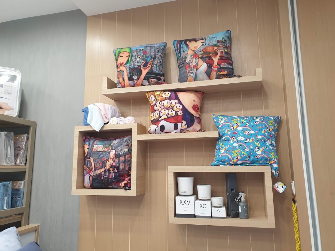 A stylish wall display at Epitex featuring artistic decorative pillows, home fragrances, and rolled towels.