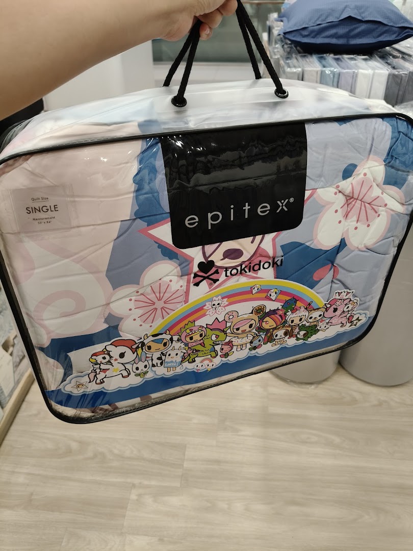 A person holds a packaged Epitex tokidoki single quilt featuring colorful characters.