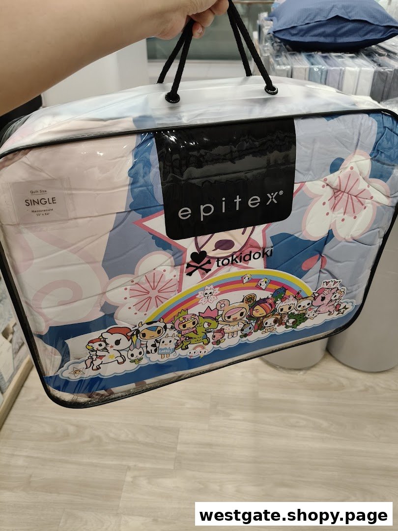 A person holds a packaged Epitex tokidoki single quilt featuring colorful characters.