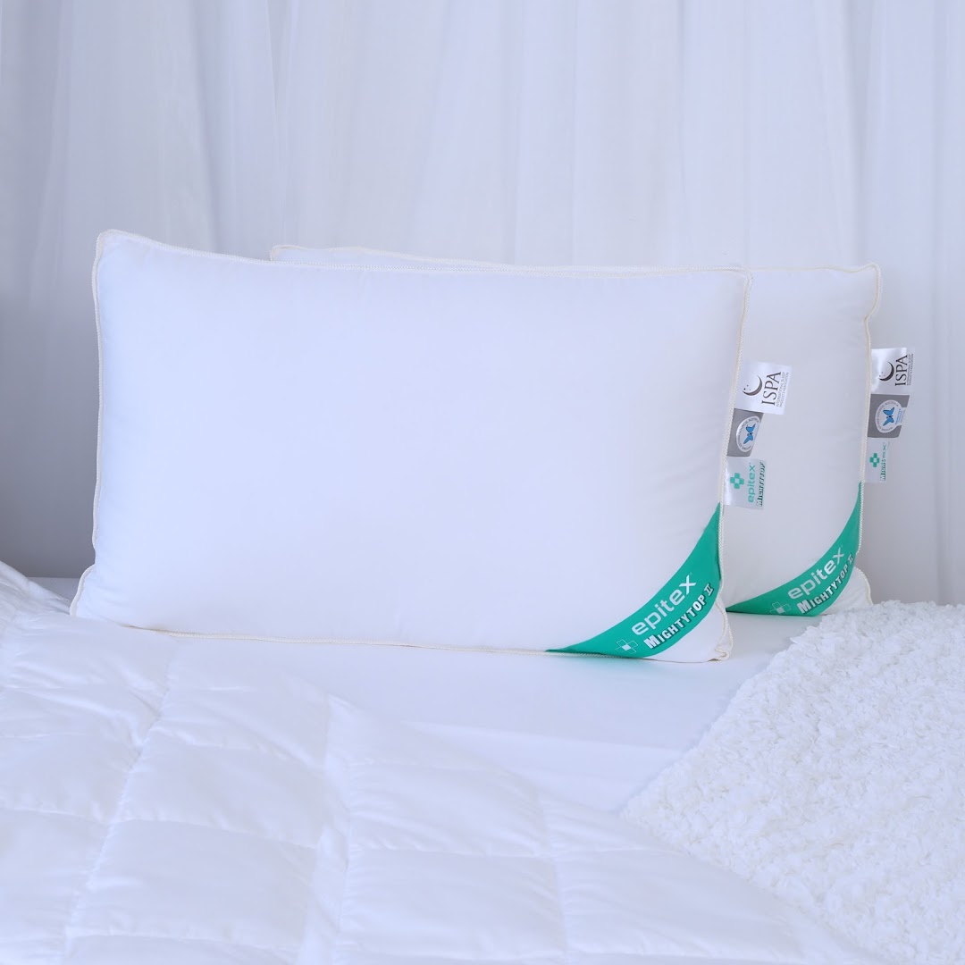 Two white Epitex pillows with green labels are displayed on a bed with white bedding.