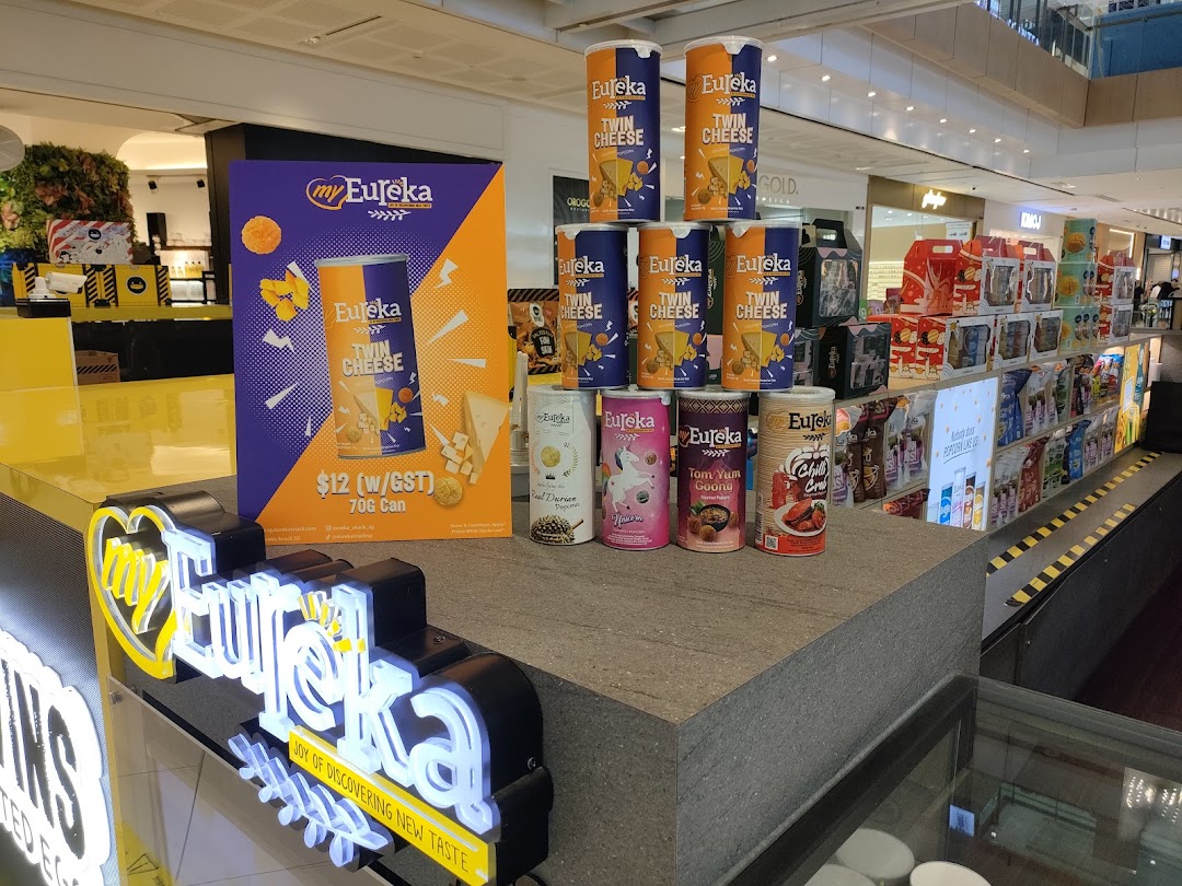 A vibrant display of Eureka popcorn products, featuring various flavors and a promotional stand for Twin Cheese.