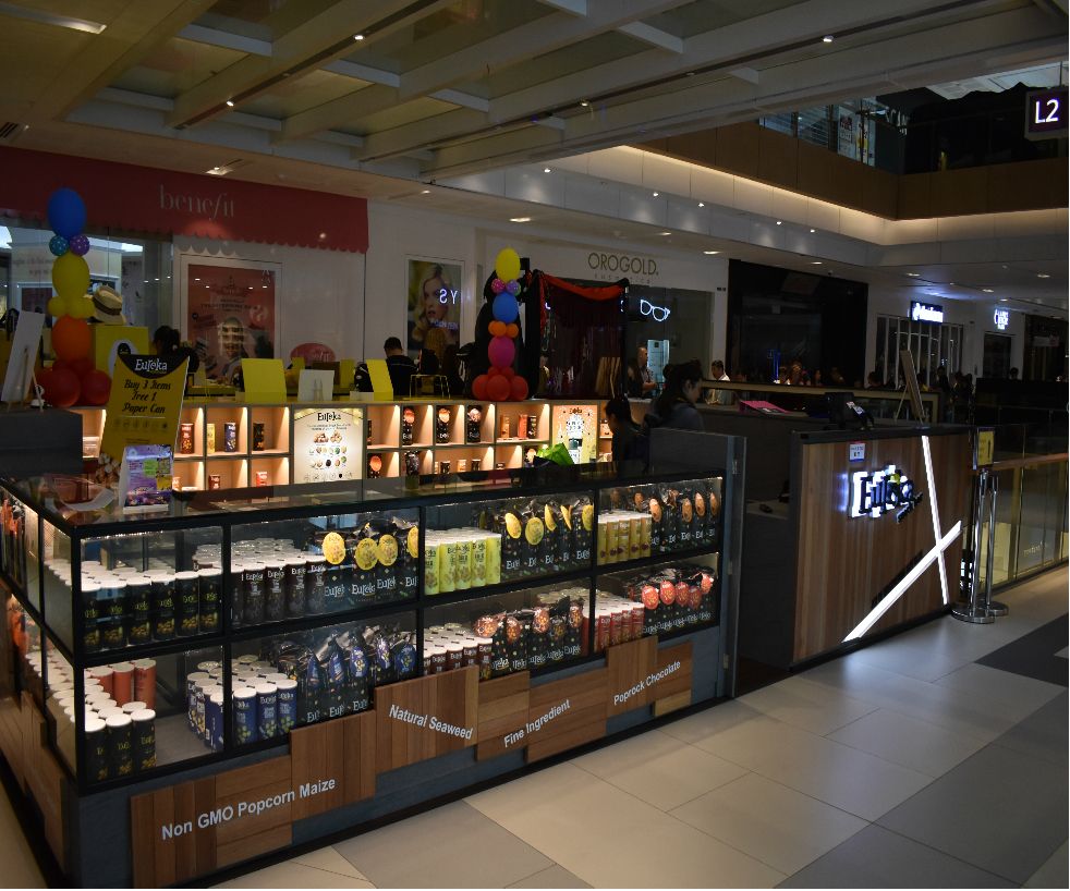 Eureka Popcorn kiosk in a mall, showcasing a variety of gourmet popcorn products and flavors.