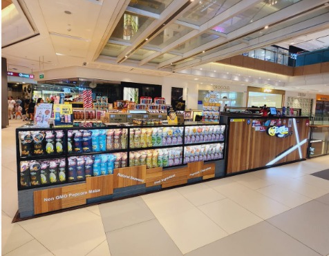 A vibrant Eureka Popcorn kiosk showcasing a wide array of packaged gourmet popcorn flavors.