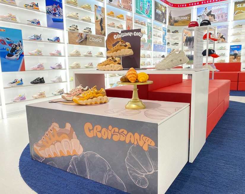 A vibrant Fila store interior showcasing a wide array of stylish sneakers and a unique 'Croissant' themed display.