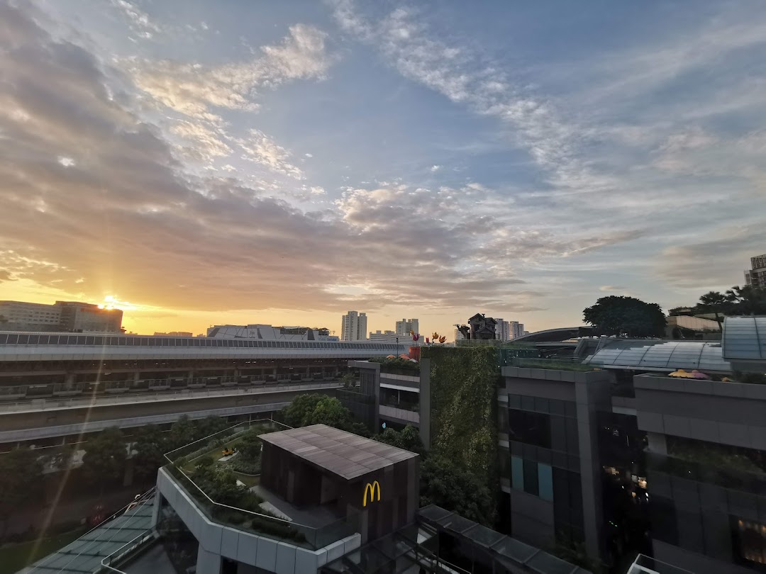 A scenic sunset view over a modern cityscape, featuring buildings, a train track, and a McDonald's logo.