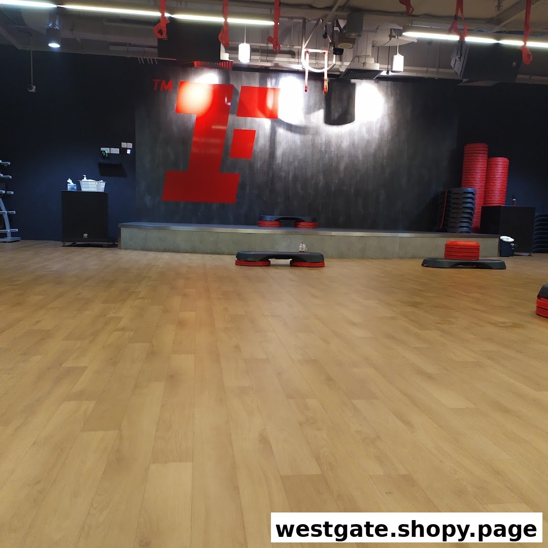 An empty fitness studio with a large red 'F' logo, a stage, and various exercise equipment.