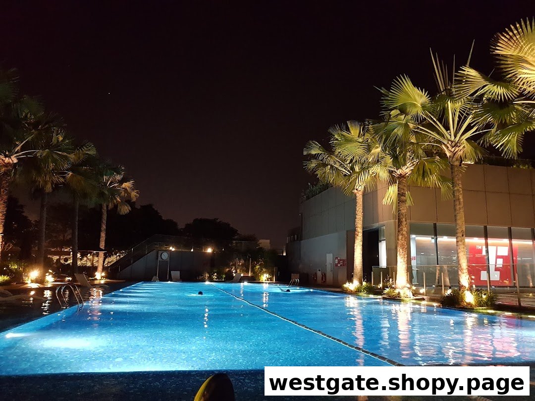 A beautifully lit swimming pool at Fitness First Westgate at night, surrounded by palm trees.