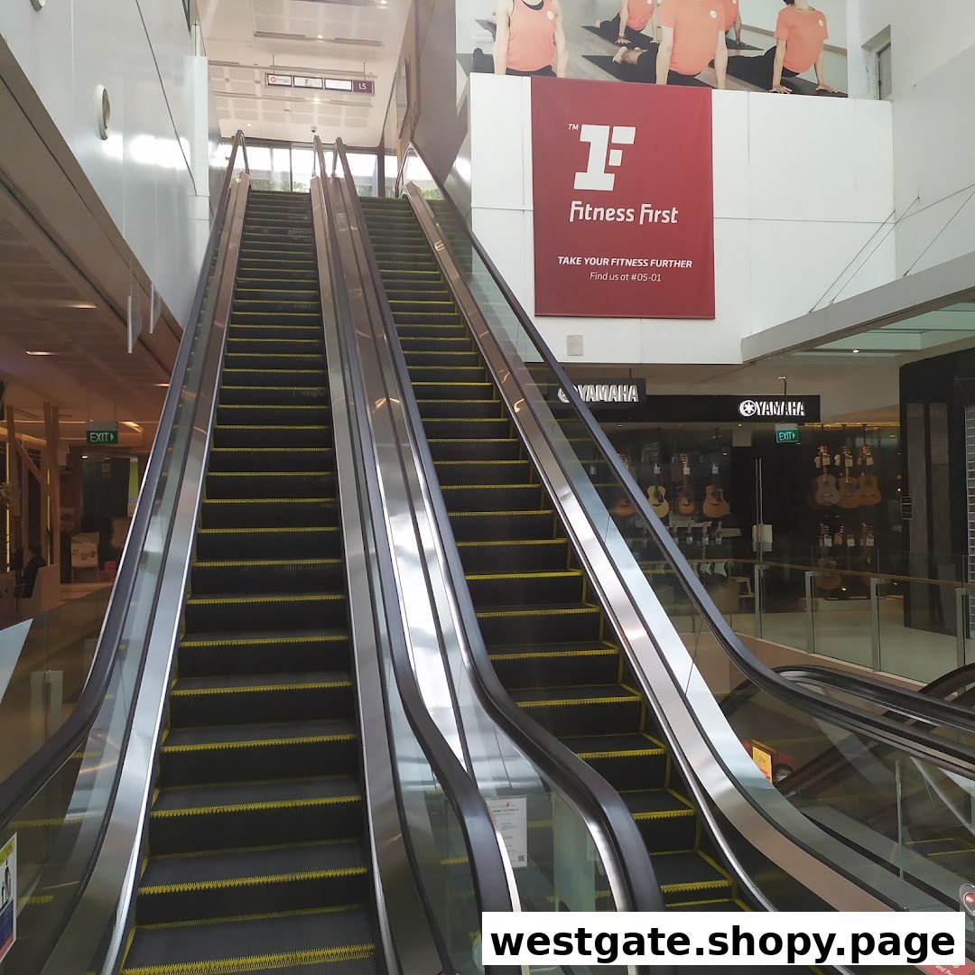 Escalators leading up to a Fitness First advertisement banner in a shopping mall.